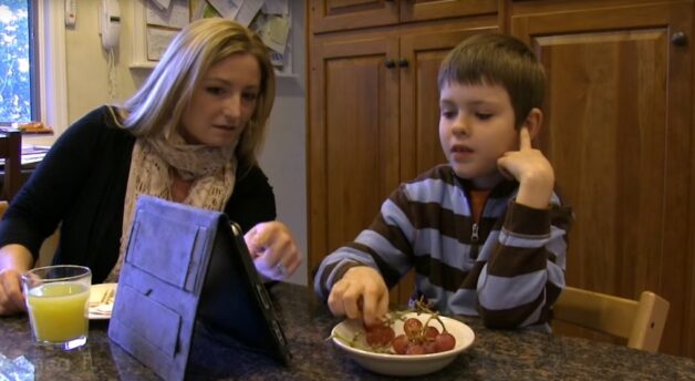 Mother child kitchen table eating grapes and talking using iPad