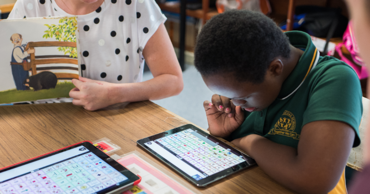 A student, teacher, and SLP sit together at table in a classroom