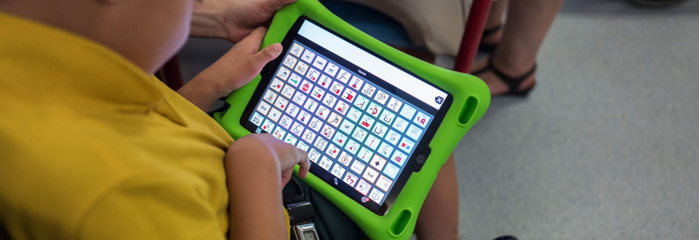 Close up photo of a boy holding an iPad with Proloquo2Go